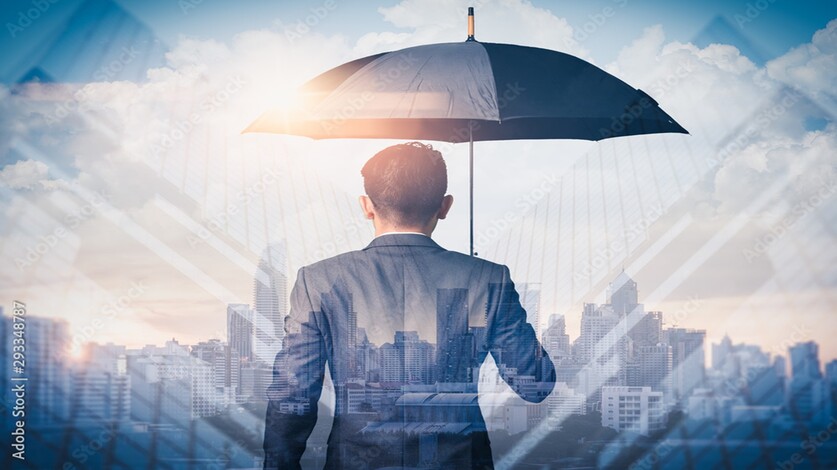 A businessman holding an umbrella stands against a cityscape backdrop, symbolizing protection and resilience in the face of urban challenges.