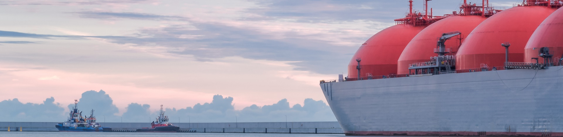 A massive ship with red tanks on it sailing through the ocean.