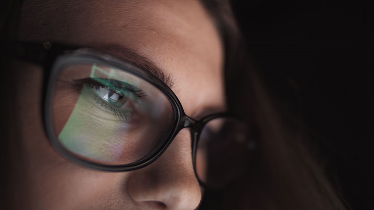 girl looking at computer reflection in glasses