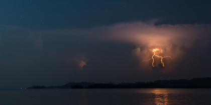 Lightning illuminates the night sky above water, creating a mesmerizing display of nature's power.